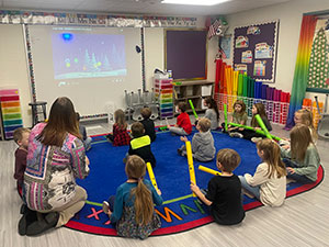 Students in Music class playing with Boomwhackers with the Superintendent