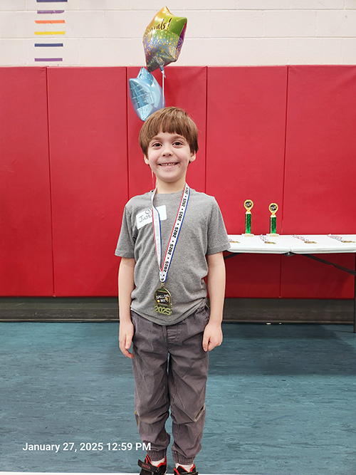 Justin posing for a picture wearing his award ribbon