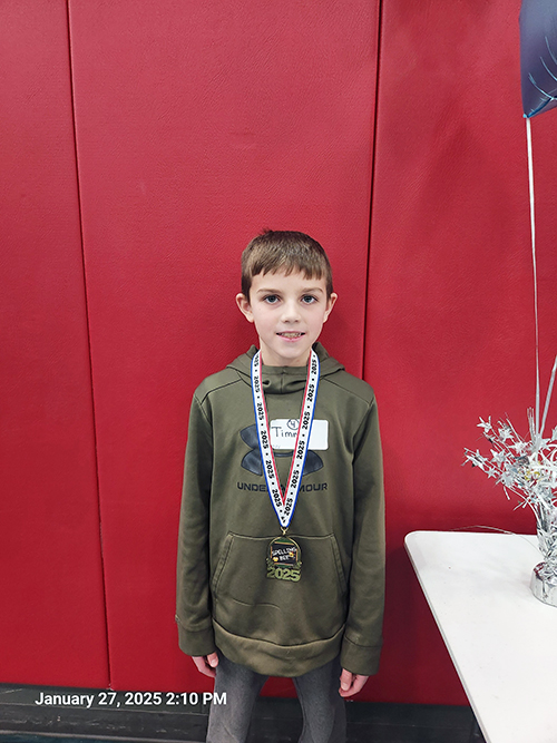 Timothy posing for a picture wearing his award ribbon