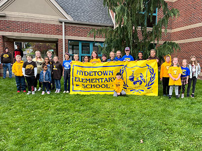 Students in front of a sign reading welcome to roberts grove park