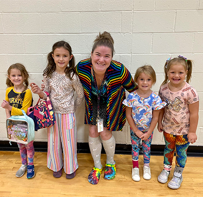 Four happy preschool students next to teacher during spirit week