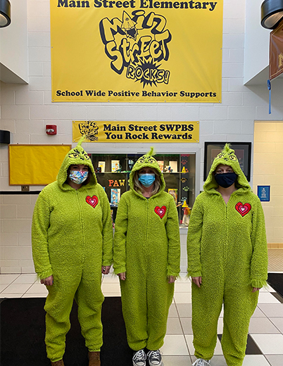 three teachers wearing grinch costumes