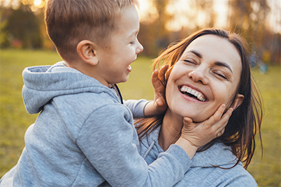 parent and daughter smiling in a park